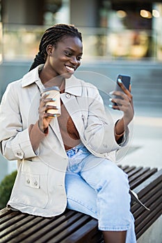 Beautiful African American woman taking selfie on mobile phone camera, showing victory sign. Emotional blogger streaming video