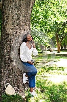 Beautiful african woman talking by phone in the park.