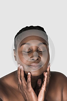 Beautiful African woman touching her face against a white background