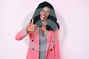 Beautiful african woman wearing business jacket and glasses doing happy thumbs up gesture with hand
