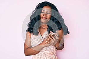 Beautiful african woman wearing casual summer clothes smiling with hands on chest, eyes closed with grateful gesture on face