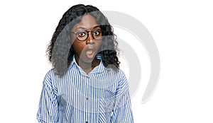 Beautiful african young woman wearing casual clothes and glasses afraid and shocked with surprise and amazed expression, fear and
