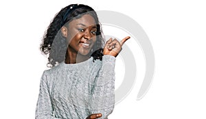 Beautiful african young woman wearing casual winter sweater with a big smile on face, pointing with hand and finger to the side