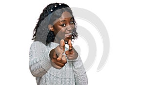 Beautiful african young woman wearing casual winter sweater pointing fingers to camera with happy and funny face