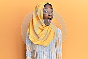 Beautiful african young woman wearing traditional islamic hijab scarf afraid and shocked with surprise expression, fear and