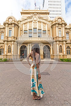 a beautiful afro-descendant woman from behind viewing the National Post and Telegraph Building of Costa Rica in the city of San