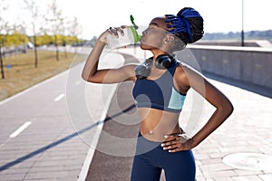 Beautiful afro fitness athlete woman drinking fresh water after workout exercising
