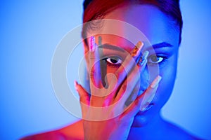 Beautiful afro woman clothing face with hand, looking through fingers at camera