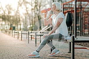 Beautiful aged sports-oriented woman drinking water from the bottle