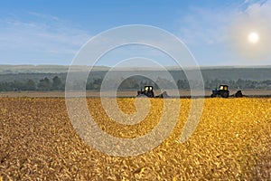Beautiful agricultural landscape with filed of golden wheat and two old tractors equipped with seeders photo
