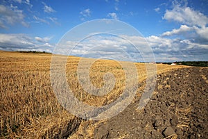 Beautiful, agricultural landscape with reaped wheat field and blue sky with dramatic clouds