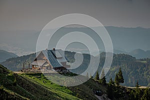 Beautiful alpine hut on Golica mountain visible from above. Nice forest in the background. Slovenian alpine cottages surrounded by