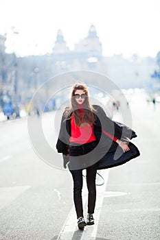 Beautiful amazing brunette woman with long wavy hairstyle in spring or fall stylish urban outfit walking on the street.