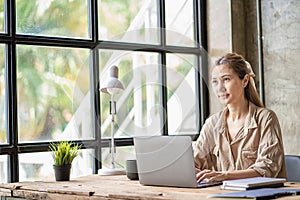 Beautiful ambitious Asian female employee working from home. girl using laptop smile like a dream Students feel inspired to write