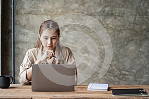 Beautiful ambitious Asian female employee working from home. girl using laptop smile like a dream Students feel inspired to write