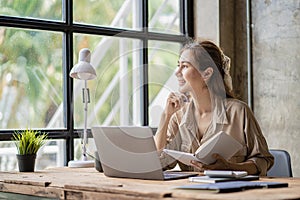 Beautiful ambitious Asian female employee working from home. girl using laptop smile like a dream Students feel inspired to write