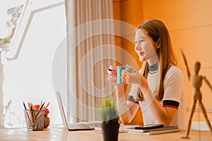 Beautiful ambitious Asian female employee working from home. girl using laptop smile like a dream Students feel inspired to write