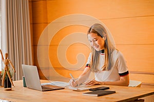 Beautiful ambitious Asian female employee working from home. girl using laptop smile like a dream Students feel inspired to write