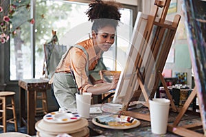 Beautiful american african artist woman painting in art studio at the university classroom