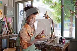 Beautiful american african artist woman painting in art studio at the university classroom