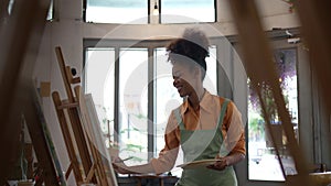 Beautiful american african artist woman painting in art studio at the university classroom