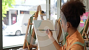 Beautiful american african artist woman painting in art studio at the university classroom