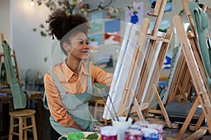 Beautiful american african artist woman painting in art studio at the university classroom