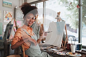 Beautiful american african artist woman painting in art studio at the university classroom