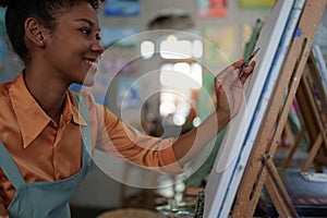 Beautiful american african artist woman painting in art studio at the university classroom