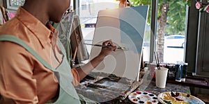 Beautiful american african artist woman painting in art studio at the university classroom