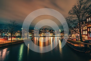 Beautiful Amsterdam city at evening time, Netherlands. Night illumination reflected in Amstel river