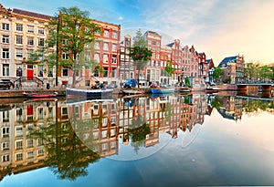 Beautiful Amsterdam sunset. Typical old dutch houses on the bridge and canals in spring, Netherlands