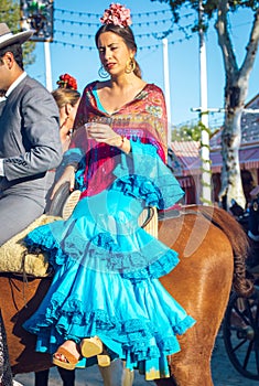 Beautiful andalusian young woman with traditional dress riding horses at the Seville`s April Fair, Seville Fair Feria de Sevilla