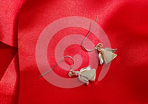 Beautiful angel earrings on red silk fabric.