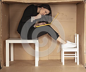 Beautiful, angry businesswoman sitting on a desk in a cramped paper office