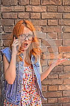 Beautiful angry and confused redhead Caucasian girl talking on smart phone