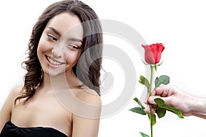 Beautiful angry girl receives one red rose. She is surprised, looking at the flowers and smiling.