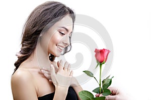 Beautiful angry girl receives one red rose. She is surprised, looking at the flowers and smiling.