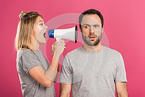 beautiful angry woman screaming with megaphone at confused man, isolated photo