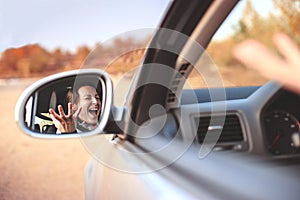 Beautiful angry young woman screaming in her car