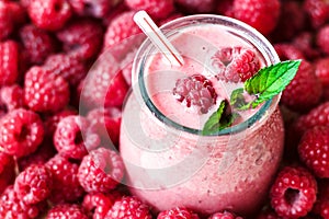 Beautiful appetizer pink raspberries fruit smoothie or milk shake in glass jar with berries background, top view.