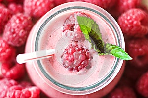 Beautiful appetizer pink raspberries fruit smoothie or milk shake in glass jar with berries background, top view.