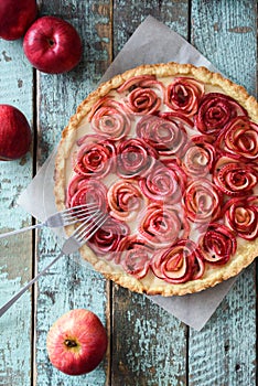 Beautiful apple rose pie with cream filling served with red apples. Homemade healthy dessert