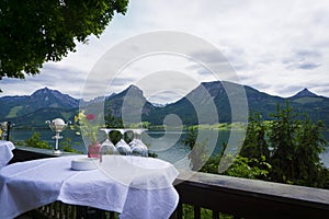 Beautiful Aps landscape with lake,  green mountains, valley, forest and table with glases of a restaurant foreground photo