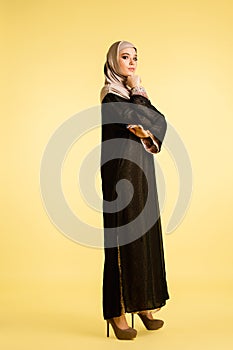 Beautiful arab woman posing in stylish hijab isolated on yellow studio background. Fashion, beauty, style concept