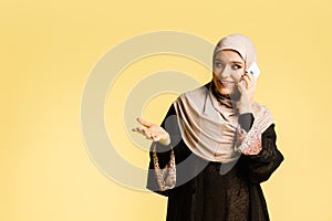 Beautiful arab woman posing in stylish hijab isolated on yellow studio background. Fashion, beauty, style concept