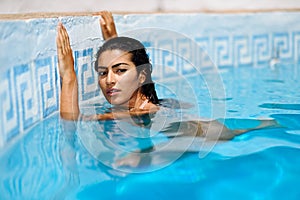 Beautiful Arab woman relaxing in swimming pool.