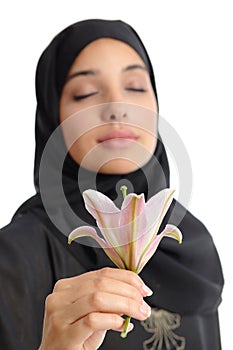 Beautiful arab woman wearing a hijab smelling a flower