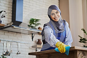 Beautiful Arabian housewife cleaning her house with a rag and gloves