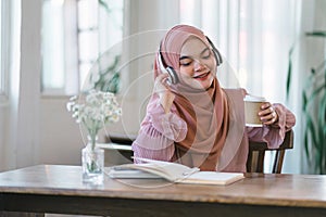 Beautiful Arabic businesswoman in a hijab enjoys a cup of tea or coffee while relaxing at creative workplace.